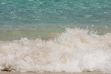 Fototapeta na wymiar a small wave breaking at the beach, turquoise water