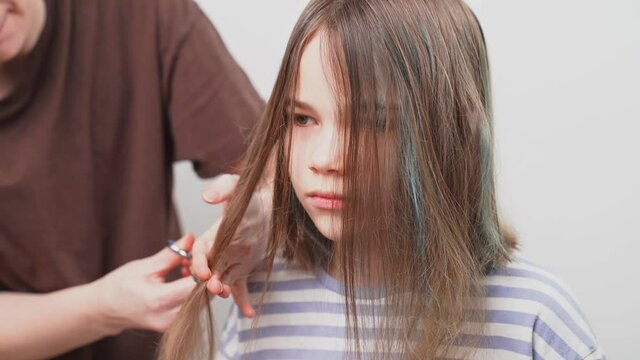 haircut. mom cuts off her daughter's hair with scissors. 