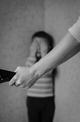 Mom with a belt stands in front of the child. The son is crying in the corner. Domestic violence against children.