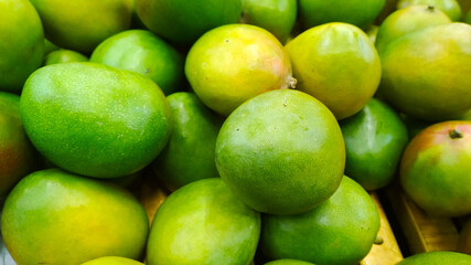 Pile of green mango background. Grocery store. Shelves with organic natural fruit in supermarket or farmer market. Fresh food. Retail industry. Discount and sale. Greengrocer. Healthy eating. Diet.