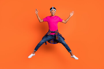 Fototapeta na wymiar Full length body size photo of young hipster jumping up playful childish laughing isolated vibrant orange color background