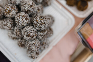 on an open display case, round handmade brown candies with sprinkles are piled up