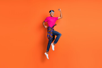 Fototapeta na wymiar Full length body size side profile photo of guy jumping high gesturing like winner isolated vivid orange color background