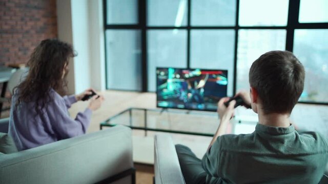happy couple playing video game with controller on play station console at home