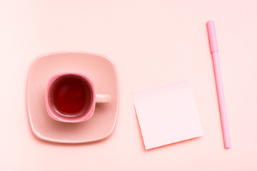 The concept is pink. Pink drink in a coffee cup, writing sheet and pen on a pink background. Top view
