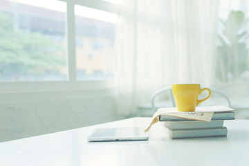 Yellow coffee cup,Workplace with white laptop, notebook and coffee on wooden desk .Coffee cups ,work desk has a laptop and a coffee cup.	