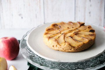 Upside-Down Apple Cake set on white cafe table background.