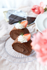 Chocolate Swiss Roll Cake with Chocolate cream filling and Strawberry set on cafe table.