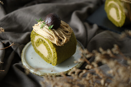 Green Tea Swiss Roll Cake With Chestnut Cream Filling Set On Cafe Table.