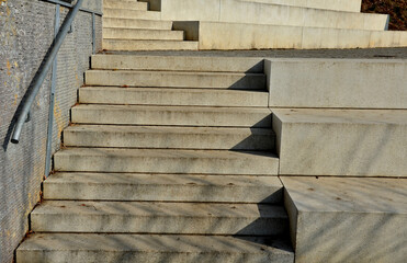 seafront with plane trees growing out of the lattice in the pavement. a beige concrete staircase...
