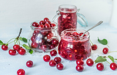 Cherry jam with fresh cherries on a blue background.