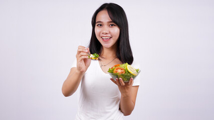 Young asian woman happy eating healthy salad with isolated white background