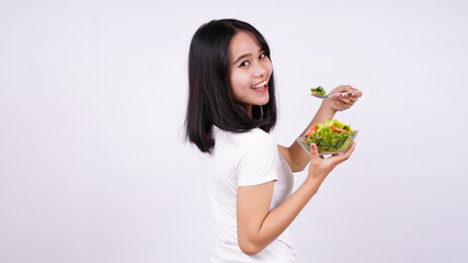 Young asian woman happy eating healthy salad with isolated white background