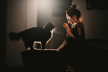 Little girl in black dress with black cat at home