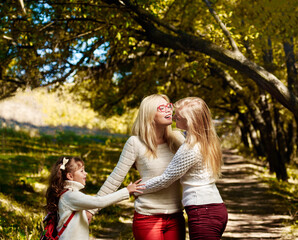 Fototapeta premium Three happy sisters playing in autumn forest on sunny warm day