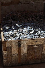 Old Treasure chest with a huge pile of different unused coins.