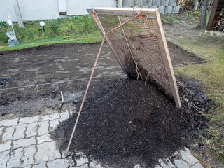Gartenerde mit einem Durchwurfsieb sieben
