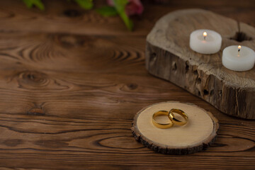 Two golden wedding rings close up on natural wooden background. Eco wedding invitation card concept. 