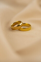 Two golden wedding rings close up on the cloth. Wedding invitation card concept. 