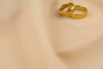 Two golden wedding rings close up on the cloth. Wedding invitation card concept. 