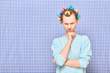 Portrait of angry disgruntled girl with colorful hair curlers on head