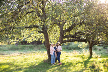 Obraz premium Family of three generation women, spending time together in green summer garden, posing under the big tree.