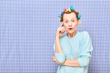 Portrait of amazed girl with bright colorful hair curlers on head