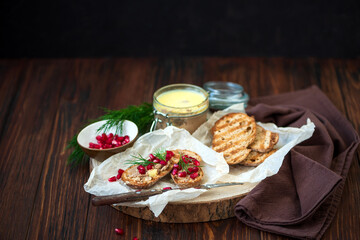 Fresh homemade chicken liver pate on bread with pomegranate seeds and dill over rustic wooden background. Soft focus. Copy space