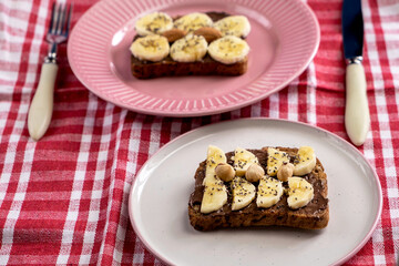 Toasted whole wheat bread with chocolate nuts paste nutella topping, banana, chia seeds, almonds and hazelnuts toast. Healthy proper nutrition for breakfast