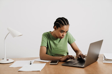 Black young woman working with laptop while sitting at table