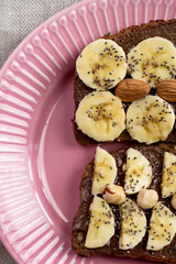 Toasted whole wheat bread with chocolate nuts paste nutella topping, banana, chia seeds, almonds and hazelnuts toast. Healthy proper nutrition for breakfast