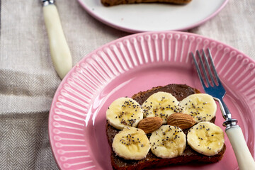 Toasted whole wheat bread with chocolate nuts paste nutella topping, banana, chia seeds, almonds and hazelnuts toast. Healthy proper nutrition for breakfast