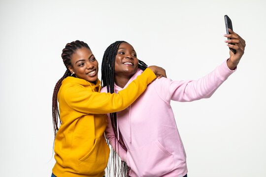 Two African American Women Taking Selfie Photos With Her Cell Phone On Gray Background