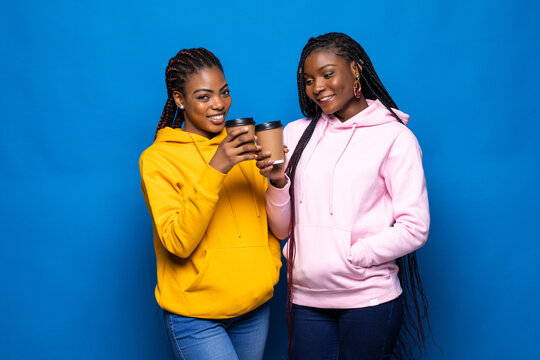 African woman having fun with her best friend frink coffee to go on blue background.