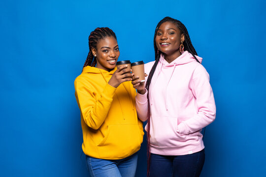 African woman having fun with her best friend frink coffee to go on blue background.
