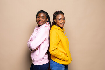 Obraz premium Portrait of two cheerful young women standing together isolated over beige background