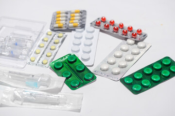 pills in packages of different types with syringes on a white background
