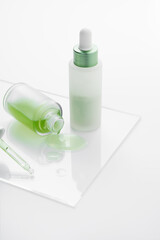 Two glass bottles with serum. spilled liquid and pipette on peace of glass. Shot in the studio on a white background