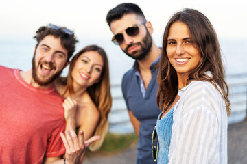 Portrait of young people having fun outdoors in the summer with the sea in the background. Togetherness concept, shallow depth of field with focus on the woman on the right
