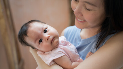 portrait of asian baby infant in mother parent arm holding and smile. happy woman embrace lovely daughter.