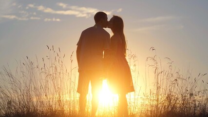 Silhouettes of happy lovers kissing at sunset.