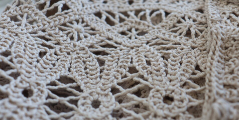 knitted lace, crochet, beige. The material is folded randomly on a horizontal surface. Sample of fabric. Trends, fabric supply, garment production, crochet fabric, triumphant return,