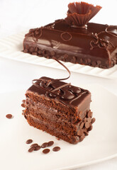 A styled Chocolate cake and a piece of that cake in front of it.