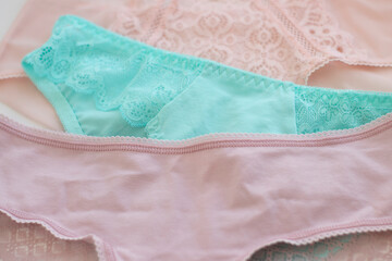 women's, lace panties, pink, turquoise, laid out on a light background. Difficulties in choosing underwear, fashion, health, beauty. Women's multicolored lace panties