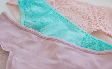 women's, lace panties, pink, turquoise, laid out on a light background. Difficulties in choosing underwear, fashion, health, beauty. Women's multicolored lace panties