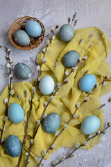 Vertical Easter composition. Gray marble eggs, yellow napkin and willow branches on a gray background. View from above