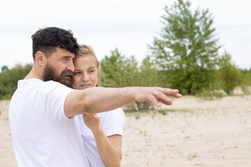 Bearded man points his hand to the side and tells his woman about something.
