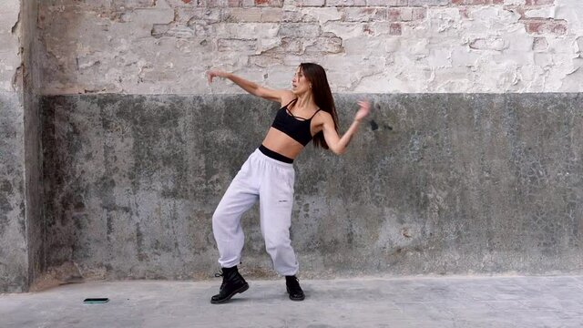 Female hip-hop dancer performing in front of flaking wall