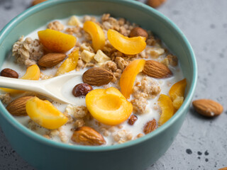 Delicious and healthy food for breakfast. Muesli with milk, pieces of apricot fruit, hazelnuts and almonds