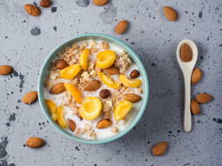 Fototapeta na wymiar Delicious and healthy food for breakfast. Muesli with milk, pieces of apricot fruit, hazelnuts and almonds